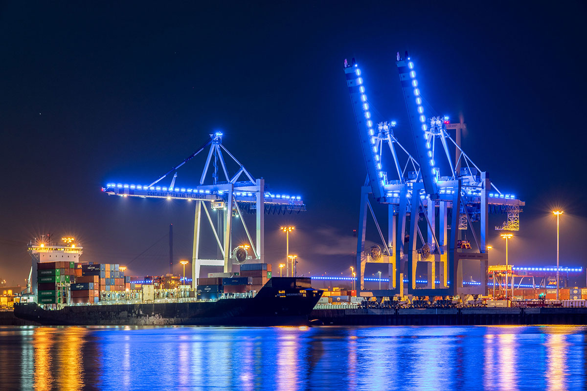 Containerterminal Tollerort in Hamburg bei Nacht mit beleuchteten Hafenkränen und Containerschiff während Blue Port Hamburg
