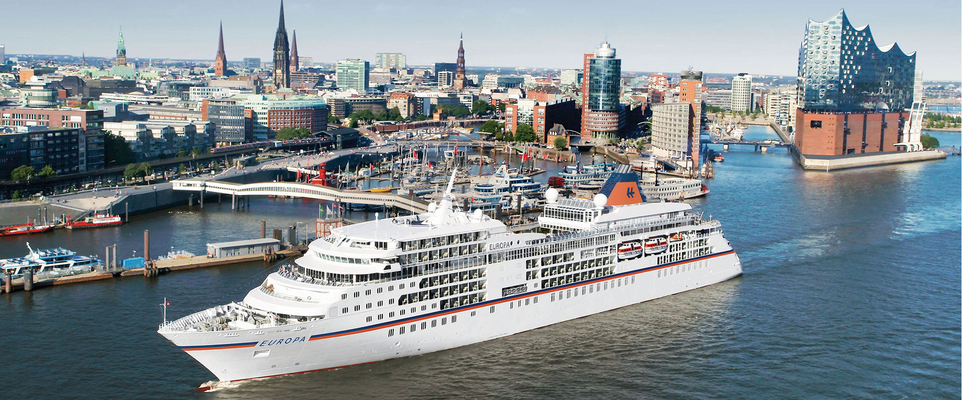 Kreuzfahrtschiff EUROPA fährt durch den Hamburger Hafen, im Hintergrund die Elbphilharmonie und die Skyline der Stadt.