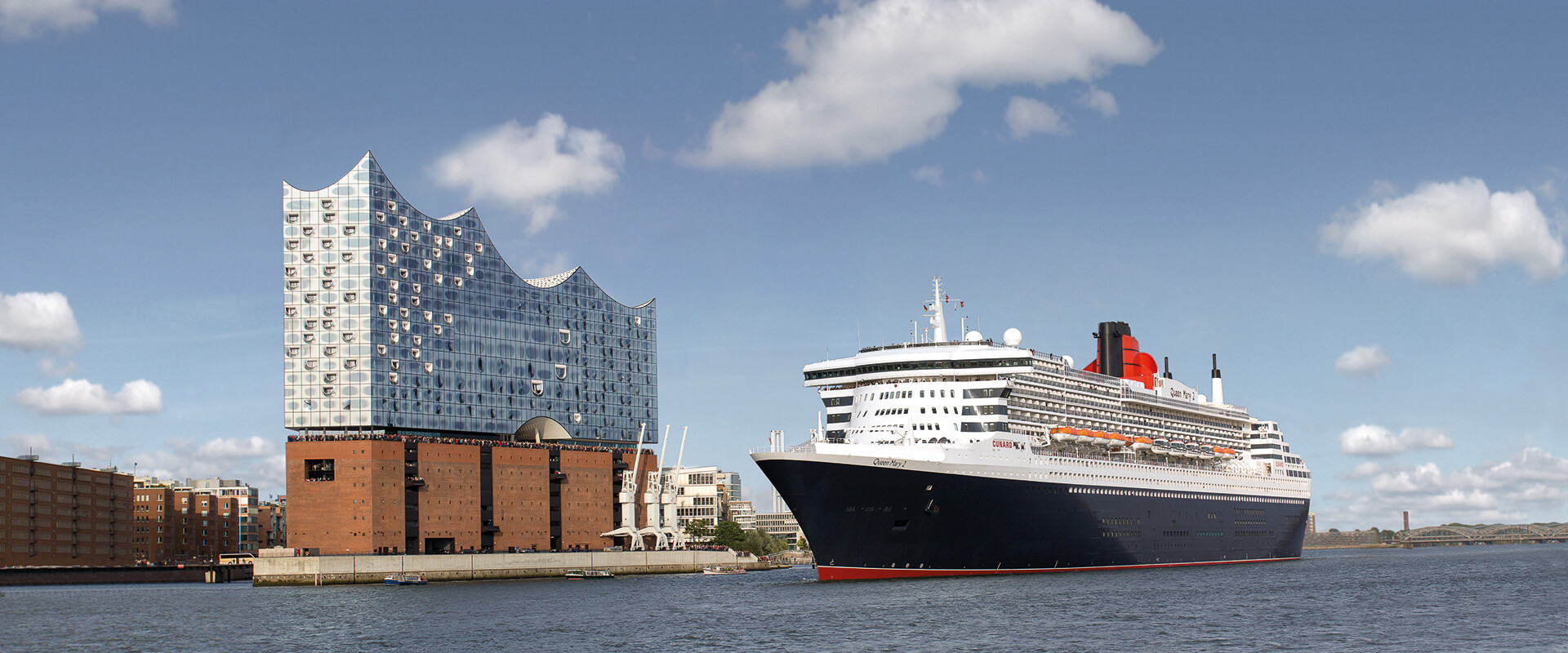 Kreuzfahrtschiff Queen Mary 2 vor der Elbphilharmonie in Hamburg bei klarem Himmel