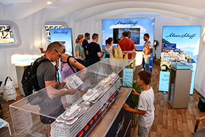 Menschen betrachten ein Modell der Mein Schiff Kreuzfahrt im Ausstellungsraum von TUI Cruises
