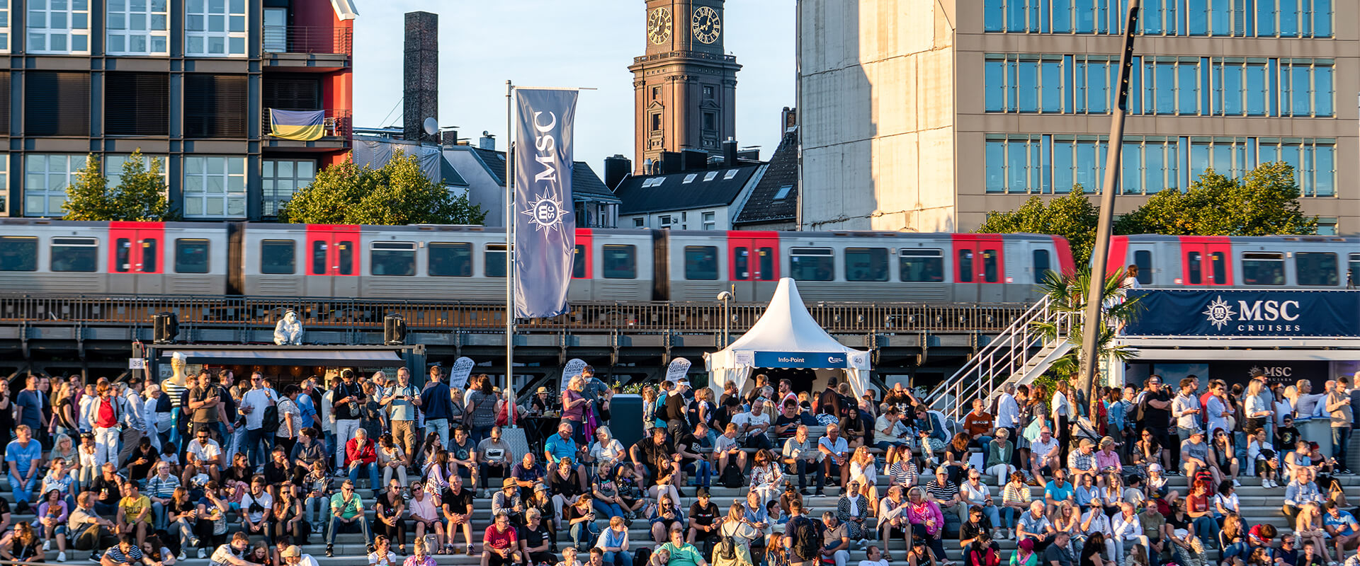 Zuschauer-auf-Jan-Fedder-Promenade Zuschauer sitzen auf Stufen auf der Jan-Fedder-Promenade bei den Hamburg Cruise Days und blicken auf die Elbe